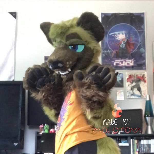 Jin A person wearing the partial fursuit of Jin, a green hyena. Their paws are raised to shoulder level, and the front of their body is turned away from the camera.