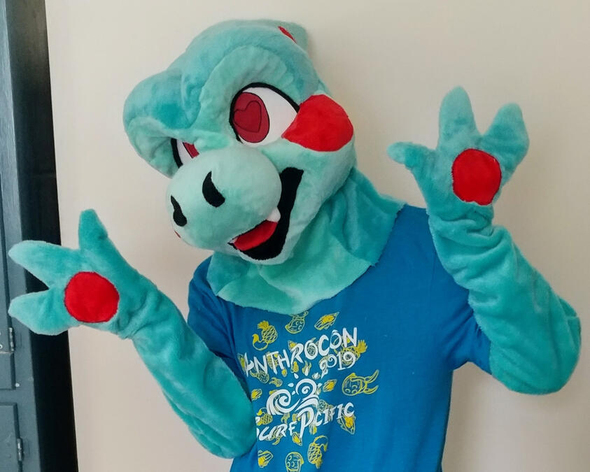 clarence2 A person wearing the Clarence fursuit. They have their hands up and their head tilted to the side.